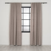 Pair of patterned curtains hanging on a rod in front of a window with a white wall background.